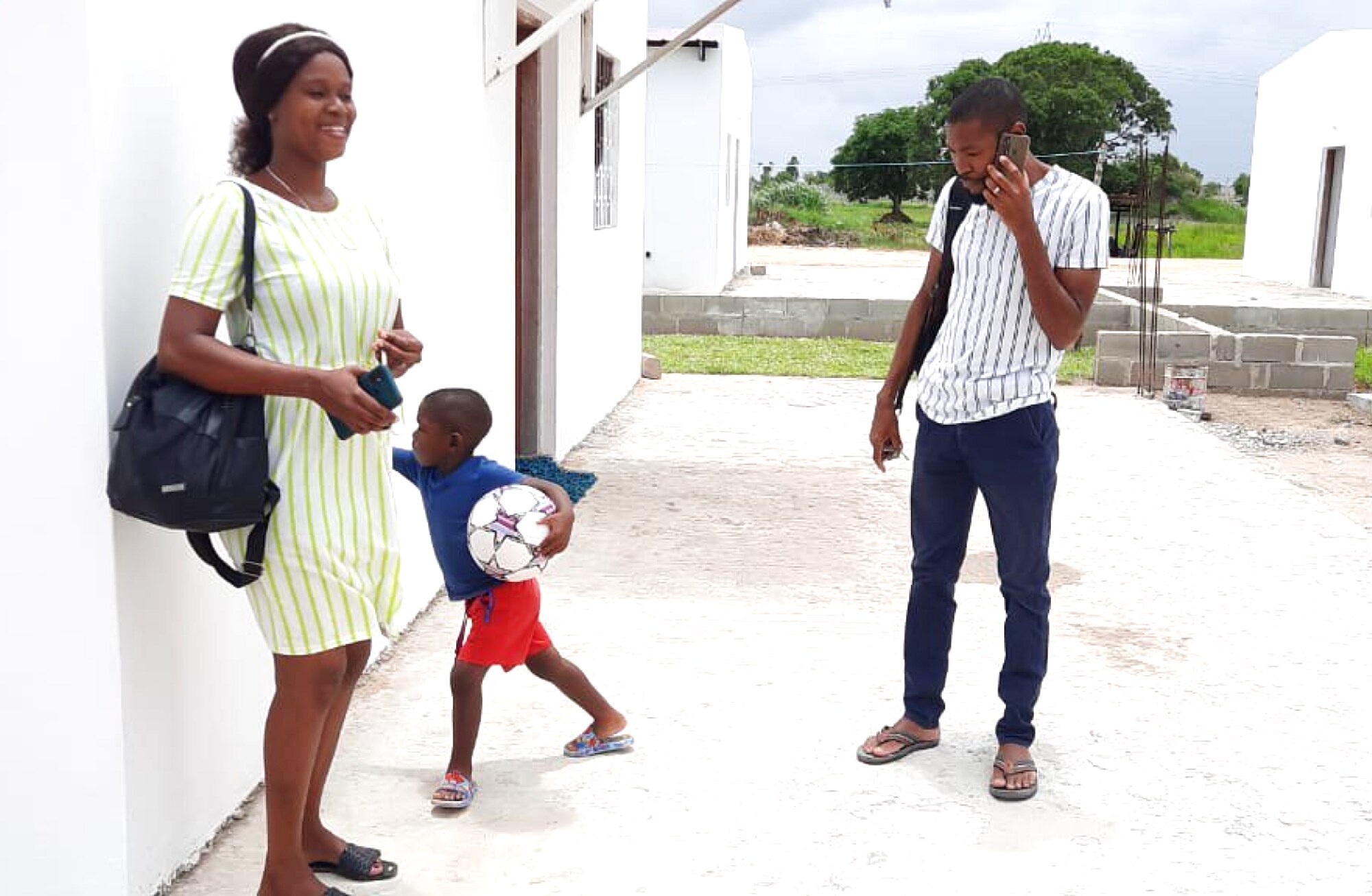 A family outside their newly-built home in Mozambique, the child playing with a football.