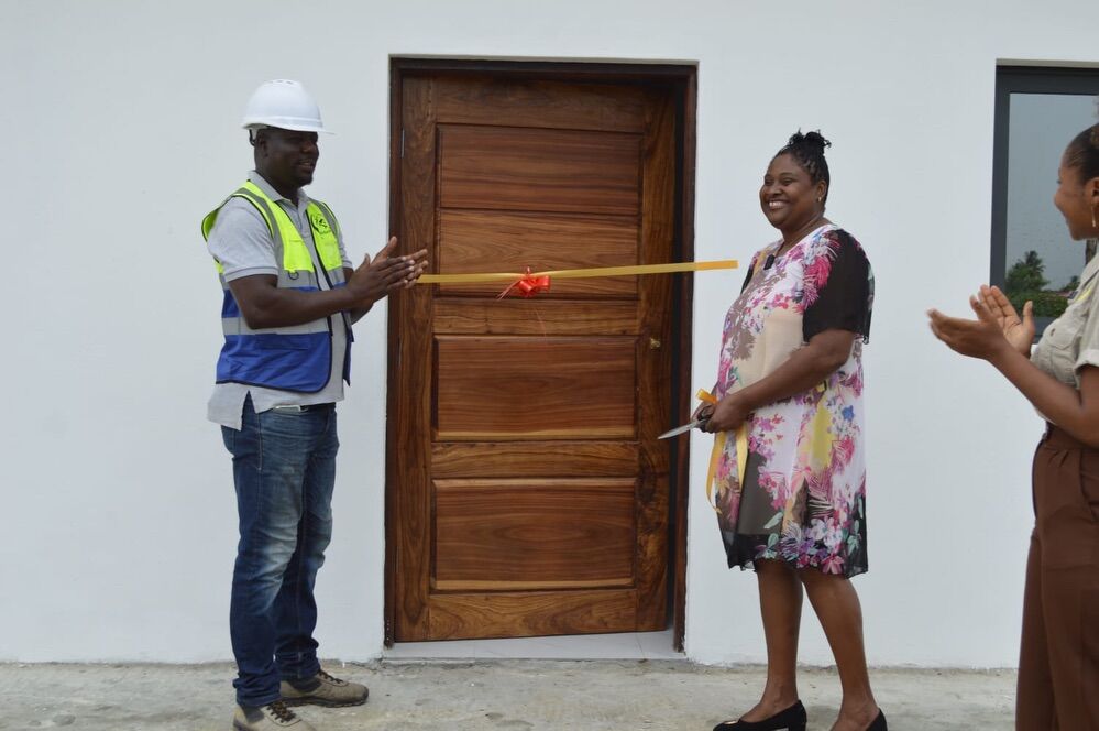 Ribbon-cutting at a home handover — builder and homeowner at the front door
